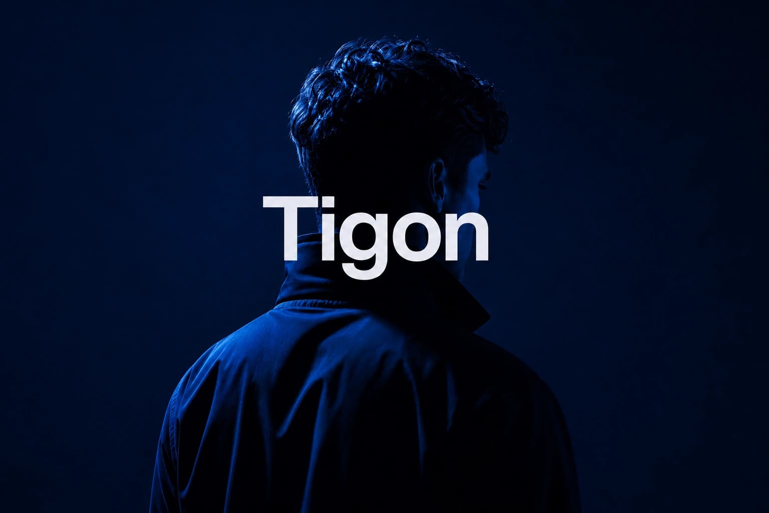 Blåbelyst person sett bakfra med stor hvit Tigon-typografi