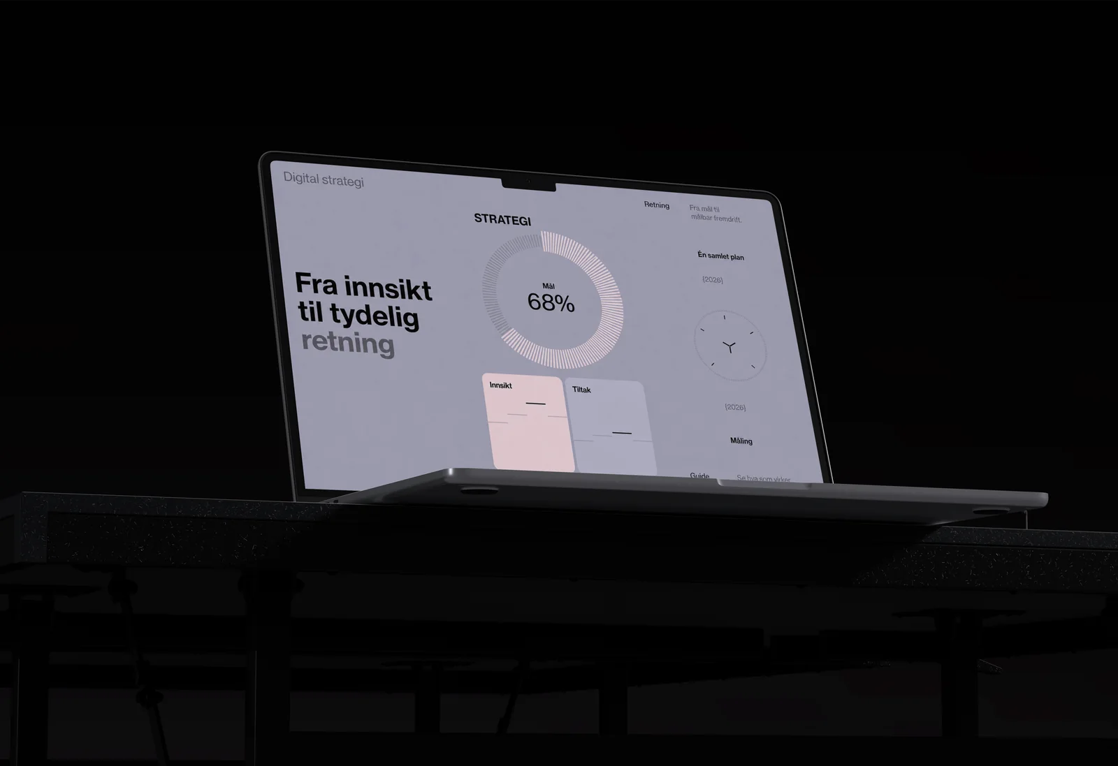 Laptop på et mørkt bord i svakt lys med en strategiflate som viser måloppnåelse