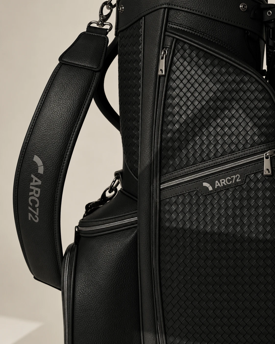 Nærbilde av en sort ARC72-golfbag i flettet skinn med symbolet på lommen og skulderstroppen.