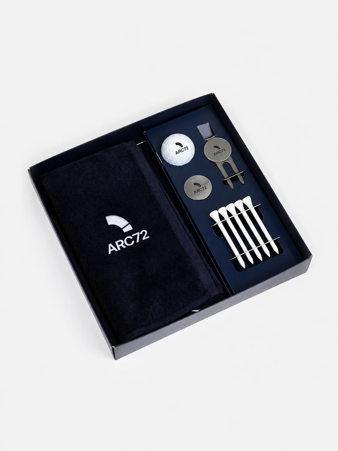 Marineblå gaveeske med håndkle, golfball, ballmarkører, pitchgaffel og tees med ARC72-merket.